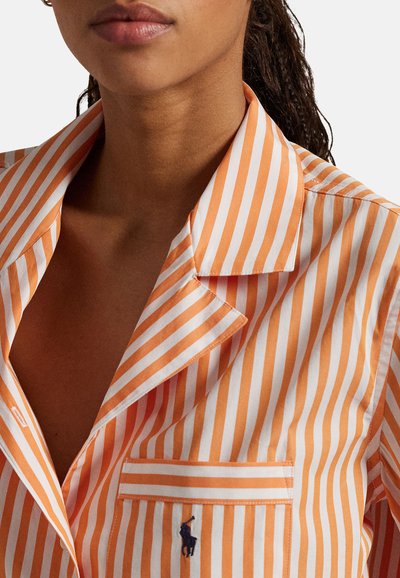 Pomarańczowo-biała koszula w paski z kołnierzem z wycięciem, kieszenią na piersi oraz haftowanym logo. Tkanina wydaje się gładka i świeża.
