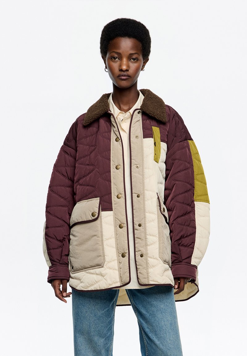 Chaqueta acolchada en burdeos, beige y oliva con diseño de acolchado texturizado, cuello con ribete de piel sintética y dos bolsillos frontales con tapetas de botón.