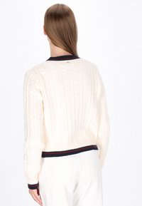 Maglione crema a coste con colletto e orlo a strisce navy e bordeaux. Design cropped con maniche lunghe e tessuto strutturato.