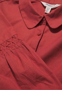 Rode blouse met kraag, vervaardigd uit een textured stof, met knoopsluiting en geplooide details op de mouwen voor een extra ontwerpelement.