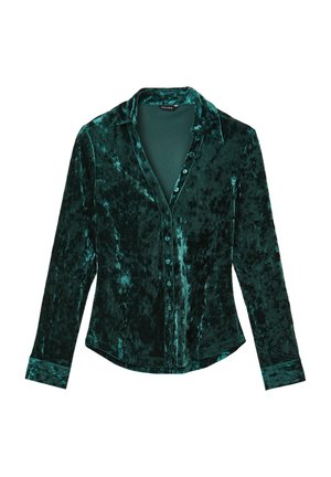 Chemise en velours vert profond avec col, manches longues, fermeture à boutons sur le devant et variations de texture subtiles à travers le tissu.