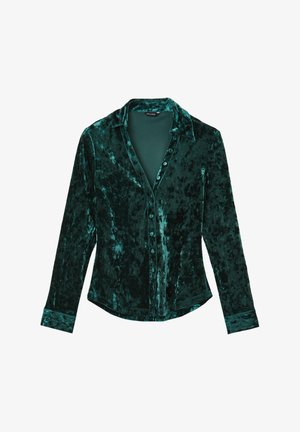 Velvet shirt in deep green with a collar, long sleeves, front button closure, and subtle texture variations across the fabric.