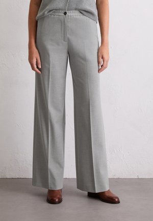 Grijze wijde trousers van een soepel materiaal met een enkele knoopsluiting en voorzakken, gecombineerd met bruine schoenen.