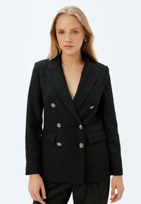 Zwarte pinstriped dubbelbreasted blazer met zilveren knopen, twee voorkruiken, gestructureerde revers en een getailleerde pasvorm. Glad textuur.