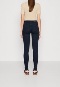 Mörkblå skinny jeans i stretchigt material, med hög midja, två bakfickor och en slät yta. Matchas med sneakers.