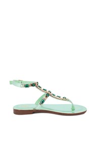 Sandalini piatti verde menta con design a infradito, caratterizzati da eleganti dettagli dorati e gemme verdi lungo le cinghie. Suola in legno marrone.