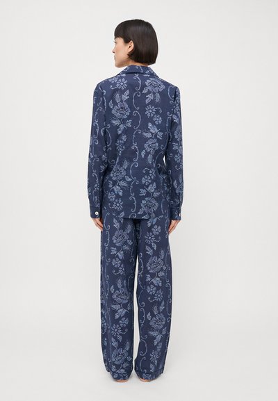 Navy floral patterned suit made of smooth fabric, featuring a collar, long sleeves, and loose-fitting trousers with a delicate design detail.