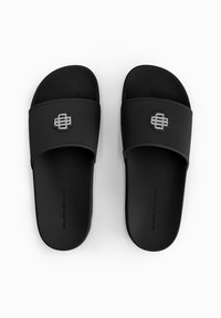 Zwarte slidesandalen met een gestructureerde rubberen band en een zachte foam voetbed. Bevat een metallic logo accent op de band. Eenvoudig ontwerp.