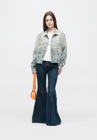 Világosszürke farmerdzseki fehér felsővel, sötétkék bővülő fazonú farmerral és narancssárga kézitáskával párosítva. Laza és modern öltözet.