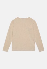 Langärmliges beige Oberteil aus weichem Stoff, mit Rundhalsausschnitt und schlichtem Design. Verfügt über eine kleine Brusttasche und dezente Nähte.