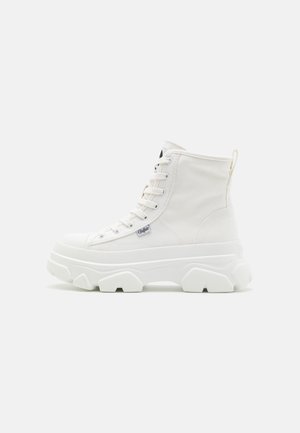 Białe sneakersy w stylu high-top z grubą gumową podeszwą, górą z płótna, okrągłym noskiem i otworami na sznurówki. Posiadają pętelkę z tyłu.