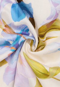 Blumengemusterter Stoff in Blau- und Grüntönen auf einem cremefarbenen Hintergrund, mit einer weichen Textur und sanftem Fall.