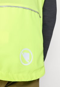 Fluorescent yellow safety vest with a gray reflective stripe and a circular logo featuring a stylized triangular shape, made from lightweight fabric.