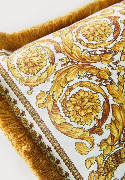 Ορθογώνιο μαξιλάρι με λουλουδάτο σχέδιο σε χρυσό και κίτρινο σε λευκό φόντο. Περιλαμβάνει απαλή, υφασμάτινη χρυσή φούντα στο περίγραμμα.