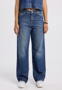 Light blue wide-leg denim jeans with a faded finish. Features classic five-pocket design and metal button closure.