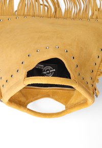 Sac à main en daim jaune avec des franges, des clous en argent et une fermeture à glissière en haut. L'intérieur présente une doublure noire avec une étiquette visible.