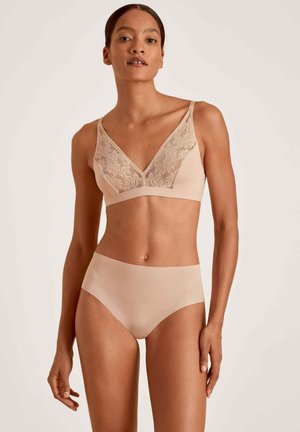 Ensemble de lingerie nude comprenant un soutien-gorge sans fil doux avec des détails en dentelle et une culotte taille haute assortie en tissu lisse et sans couture.
