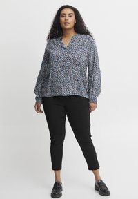 Blommig blus med blå, vita och gröna mönster, långa ärmar och V-halsringning. Matchad med svarta åtsittande byxor och svarta skov slip-on.