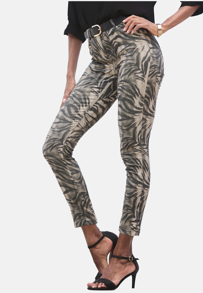 Schlanke Hosen im beigefarbenen und schwarzen Tigerprint. Aus strukturiertem Stoff mit sichtbaren Nähten, getragen mit einem schwarzen Gürtel und hohen Sandalen.