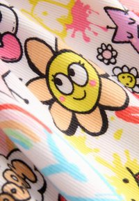 Tissu multicolore avec un sourire de fleur jaune, des motifs floraux et des éclaboussures abstraites en rose et bleu sur un fond clair.
