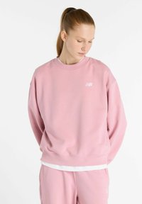 Sweatshirt en coton rose avec un col rond, coupe ample et poignets côtelés. Doté d'un logo blanc sur la poitrine gauche et d'un ourlet blanc en superposition.