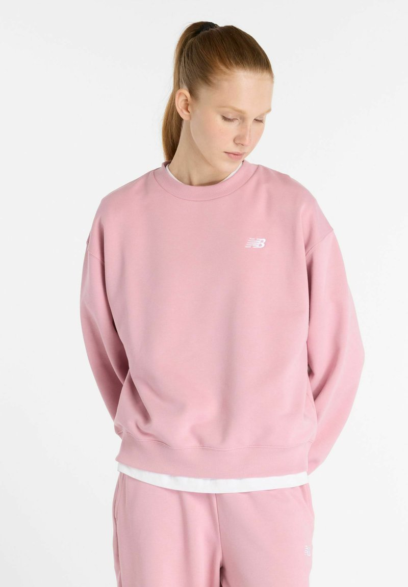 Sweatshirt en coton rose avec un col rond, coupe ample et poignets côtelés. Doté d'un logo blanc sur la poitrine gauche et d'un ourlet blanc en superposition.