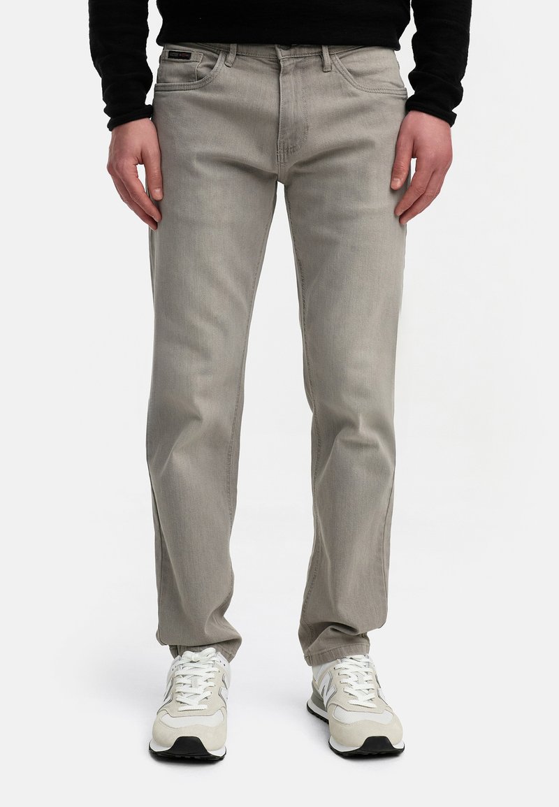 Gray denim jeans feature a straight cut, five-pocket design, and a subtle distressed texture. Paired with white and gray sneakers.