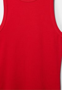 Débardeur rouge sans manches avec encolure ronde et coutures visibles le long des bords sur un fond blanc uni.