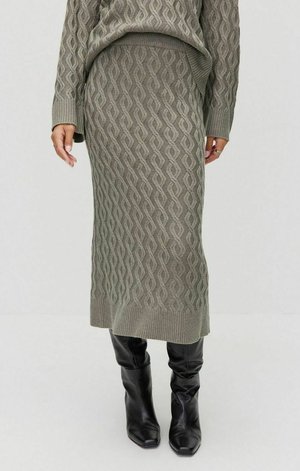 Gebreid twee-delig set in gedempt groen met een golvend patroon. Rok valt onder de knie en wordt gecombineerd met een bijpassende top en zwarte kniehoge laarzen.