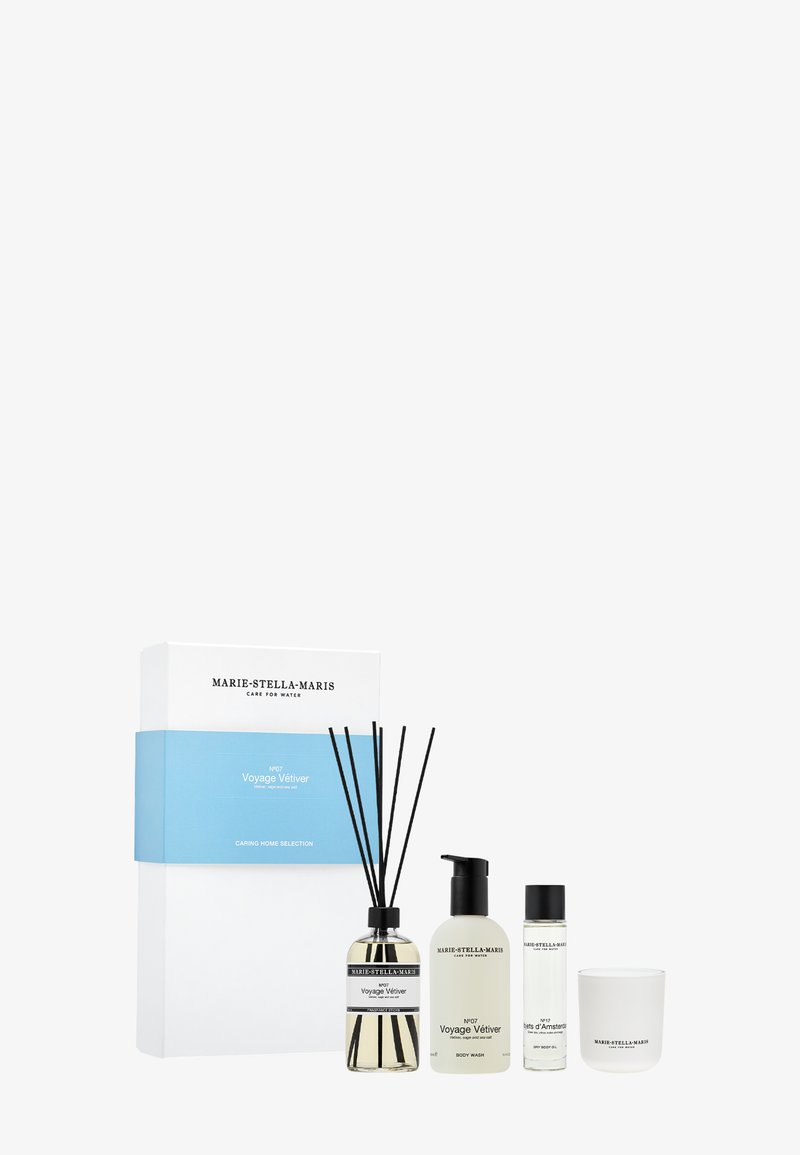 Ensemble de parfum d'intérieur comprenant un diffuseur en verre avec des tiges noires, un gel douche, un gel nettoyant et une bougie, le tout dans un emballage blanc et transparent.