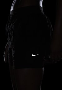 Čierne atletické šortky vyrobené z ľahkého materiálu, s elastickým pásom a bielym logom Nike na stehne.