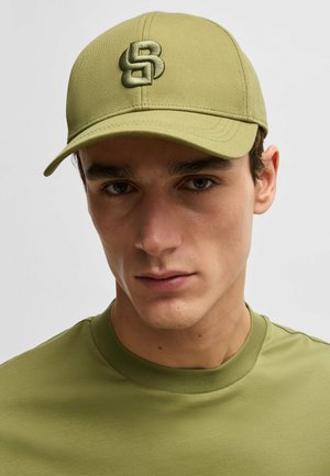 Olive green baseball cap with an embroidered logo, featuring a structured design and curved brim, paired with a matching fitted T-shirt.