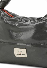 Bolso gris brillante con un diseño suave y redondeado. Presenta una etiqueta de marca blanca prominente y una cremallera roja brillante.