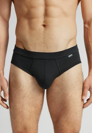 Schwarze Slips aus dehnbarem Stoff, mit einem Bund und einem Nahtdesign an der Vorderseite. Das Material wirkt glatt und hat ein mattes Finish.