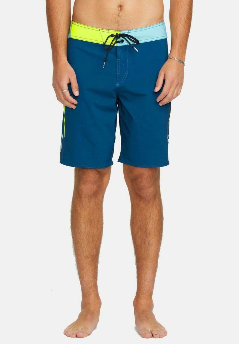 Bañador azul con una cintura en azul claro y verde neón. Cuenta con un cordón, acentos en los paneles laterales y una textura sintética suave.