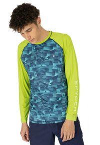 Langsleeve sportshirt in blauw geometrisch patroon met contrasterende groene mouwen. Bevat een logo op de borst en tekst op de mouw.