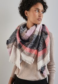 Ampio scialle a quadri in morbido tessuto testurizzato. I colori includono rosa, nero, borgogna e beige con bordi frangiati. Indossato drappeggiato intorno alle spalle.