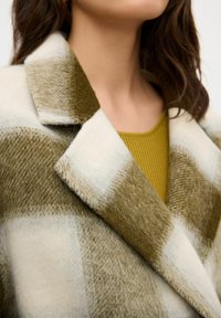 Cappotto in misto lana con un grande motivo a quadri in verde oliva e crema, dotato di colletto a punta e una finitura morbida e testurizzata.