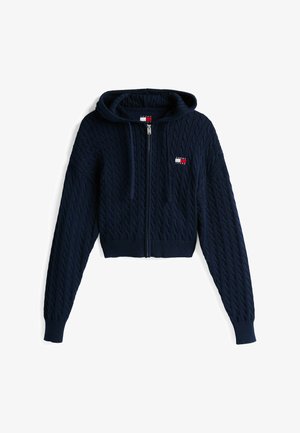 Marineblå strikket hoodie med lynlås foran, der har et struktureret kabelmønster, ribbet kant og lille brandlogo i rød, hvid og blå.
