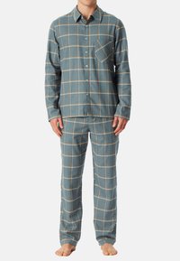 Ruokalaita pyjama-asusto sinisessä ja vaaleanruskeassa. Pitkähihainen napitettava paita, jossa rintatasku. Vastaavat housut joustavalla vyötäröllä. Pehmeä kangas.