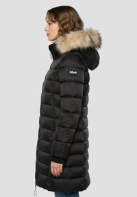 Schwarzer Steppmantel mit Kapuze und Pelzbesatz, mit gestepptem Design, elastischen Bündchen und einem Logopatch am Ärmel. Die Länge reicht bis zur Mitte der Oberschenkel.