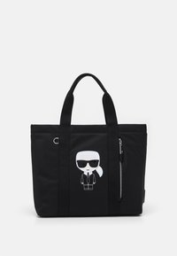 Zwarte totebag van duurzaam materiaal, met een cartoonfiguur in het wit. Het heeft stevige handvatten en een zijzak met rits.