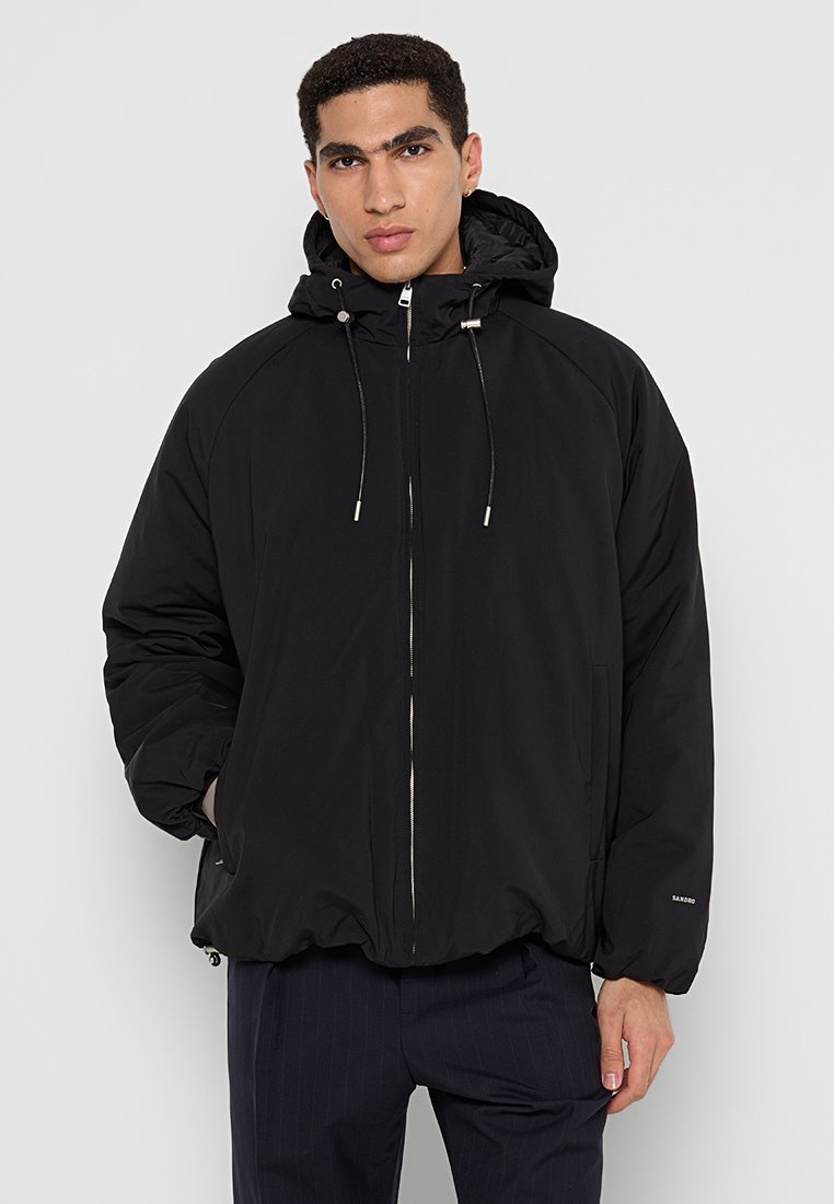 Zwarte pufferjack met capuchon, rits aan de voorkant, elastische zoom en trekkoorden, met zijzakken en een logo op de mouw.