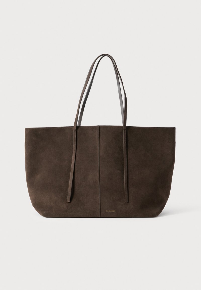 Καφέ τσάντα tote από σουέτ με μακριά δερμάτινα χερούλια, μινιμαλιστικό σχέδιο και κεντρική ραφή. Διαθέτει διακριτικό λογότυπο στη βάση.