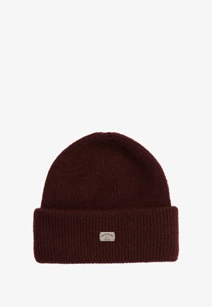 Bordeaux strikket beanie med en foldet skygge, der har et lille rektangulært mærke med teksten "Superdry NYC Athletic." Blød tekstur.