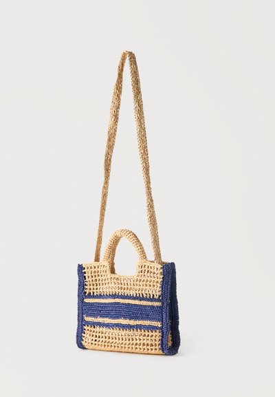 Sac à épaule rectangulaire tissé beige et bleu avec des poignées courtes et une longue bandoulière, présentant un motif ouvert et texturé.