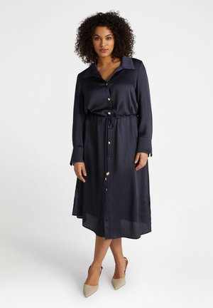 Robe bleu marine à boutonnière avec des rayures, manches longues et taille à cordon. Équipée de boutons dorés et d'une silhouette évasée fluide.