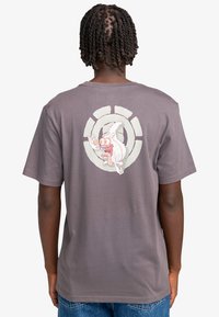 Camiseta gris de manga corta con un gráfico de un personaje de dibujos animados en la parte posterior, sobre un diseño circular. Material de algodón, ajuste relajado.