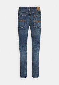 Jeans aus dunkelblauem Denim mit abgenutzter Textur. Verfügen über zwei Gesäßtaschen mit dekorativen Nähten. Gerade geschnittener Beinverlauf, Standardbund.