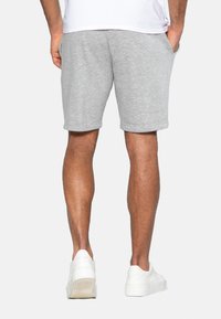 Grå bomulds shorts med en afslappet pasform, som har en elastisk talje og sidelommer, kombineret med hvide sneakers.